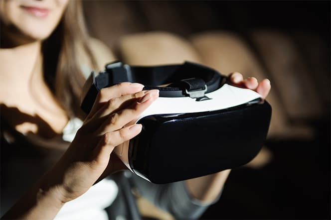 femme portant dans ces mains un casque virtuel lunette VR