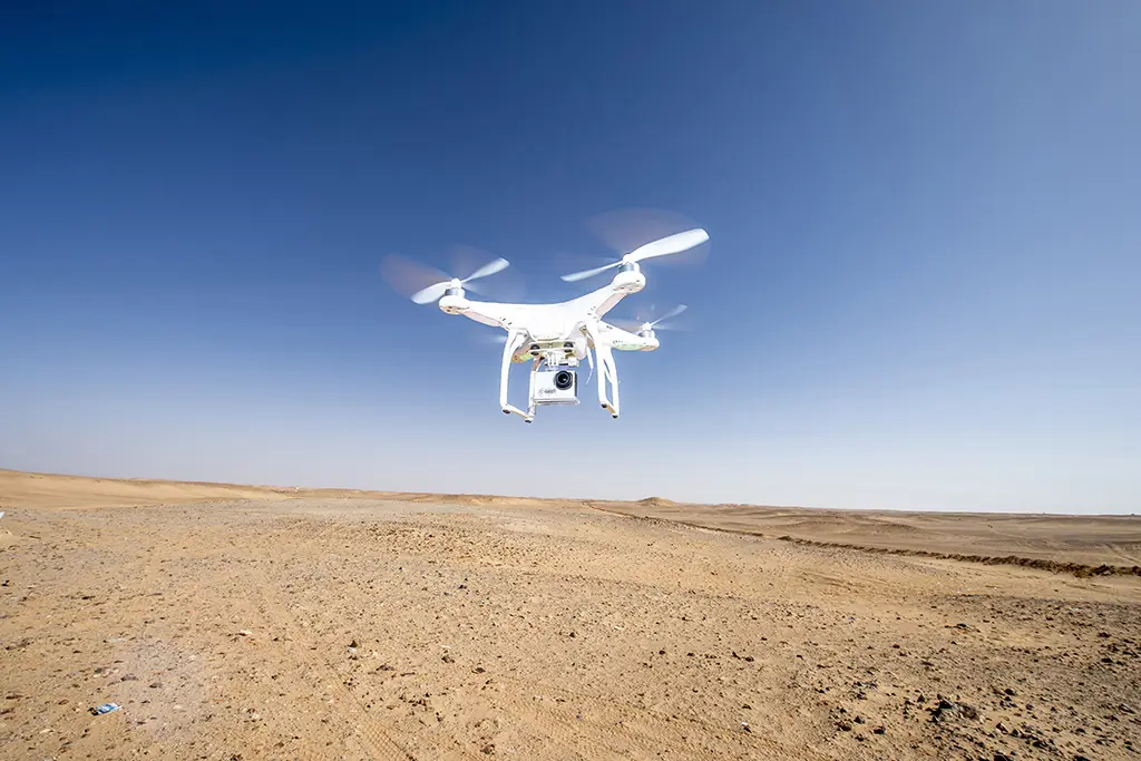 drone blanc survolant une zone desertique avec un ciel bleu