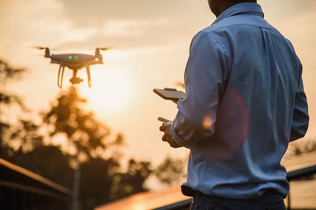 homme utilisant drone telecommande au coucher du soleil